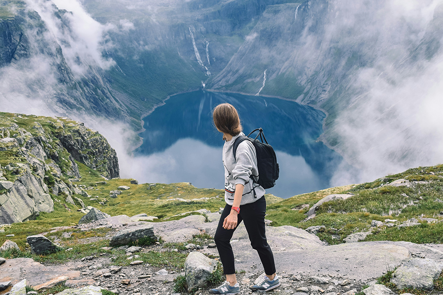 Woman backpacking on mountain looking down at a lake.