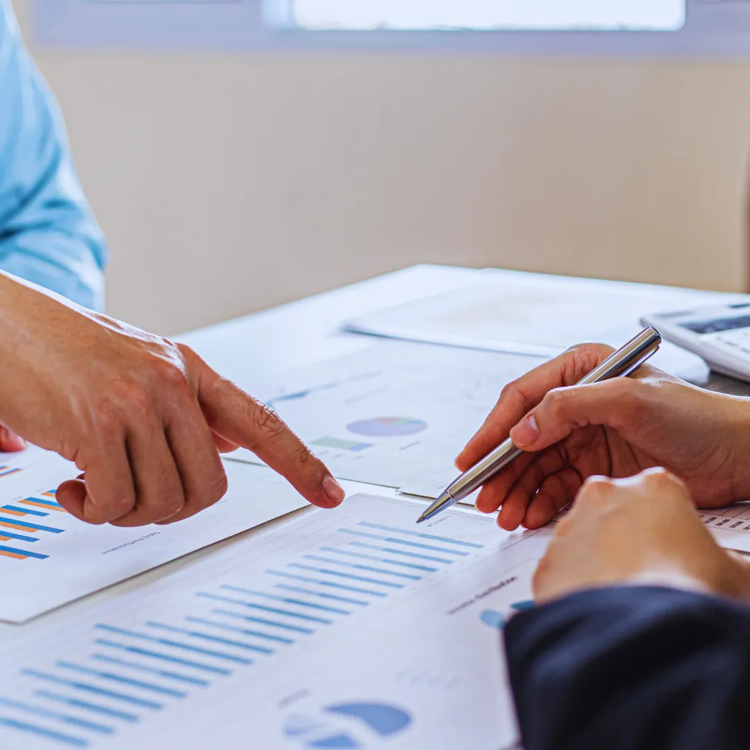 Person discussing financial documents with a financial advisor, showing charts and graphs.