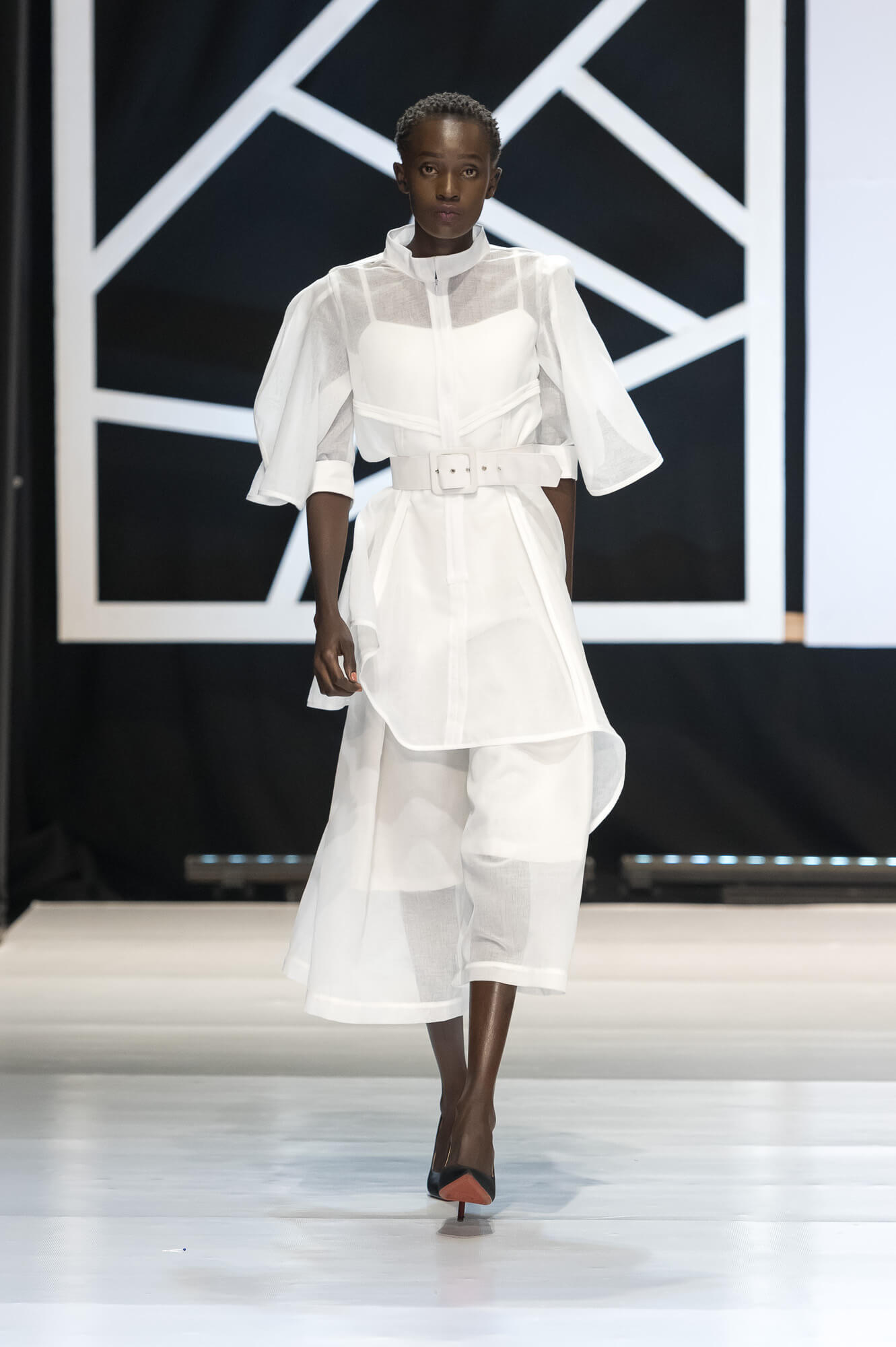 Young woman in a black dress standing against wood paneling.