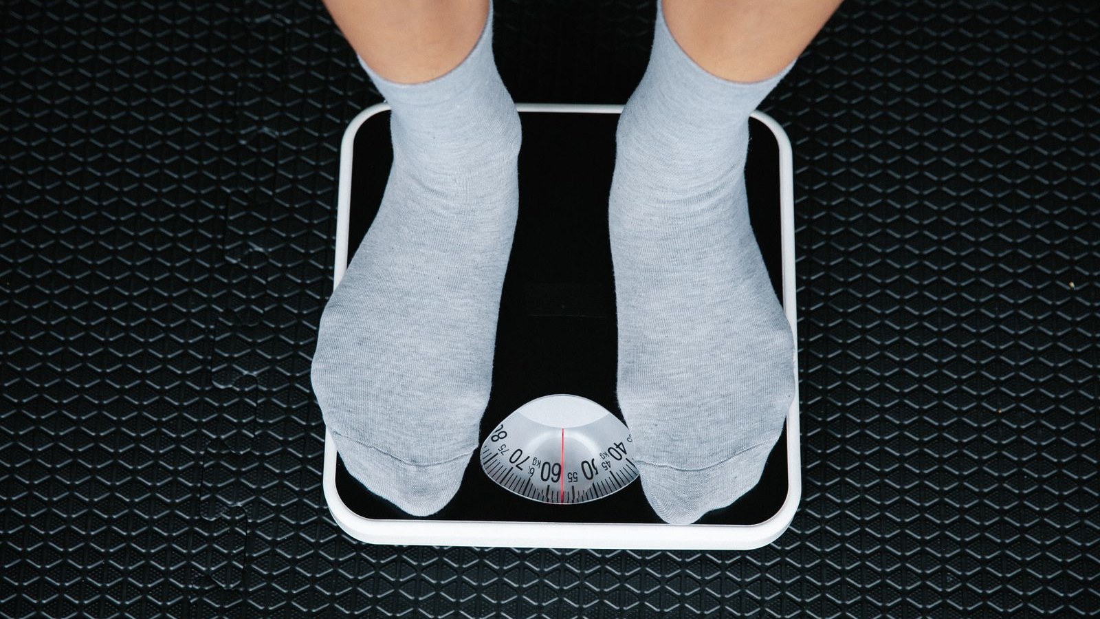 Overhead view of feet in socks standing on a bathroom scale