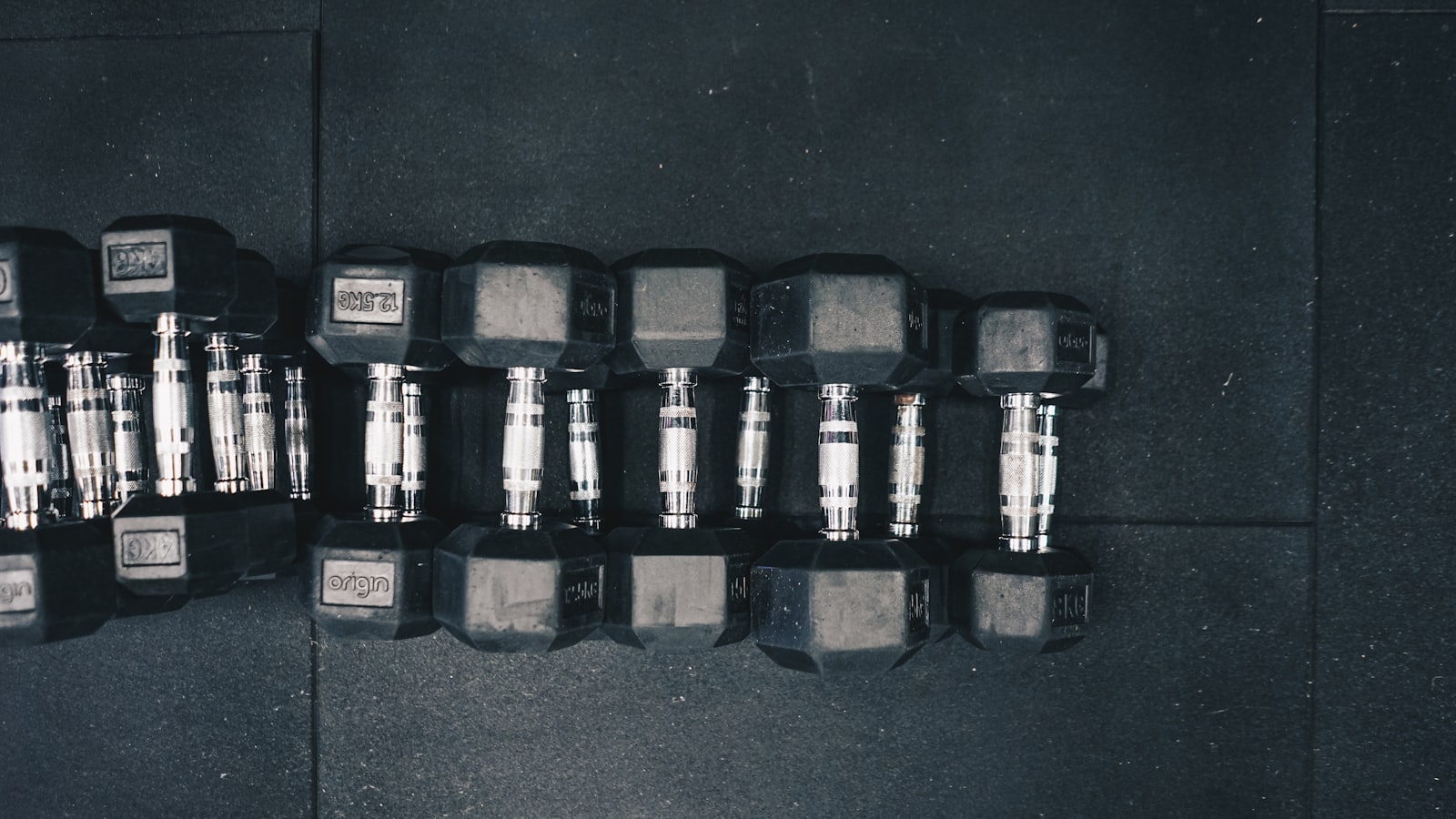 Row of black hex dumbbells arranged on a gym floor