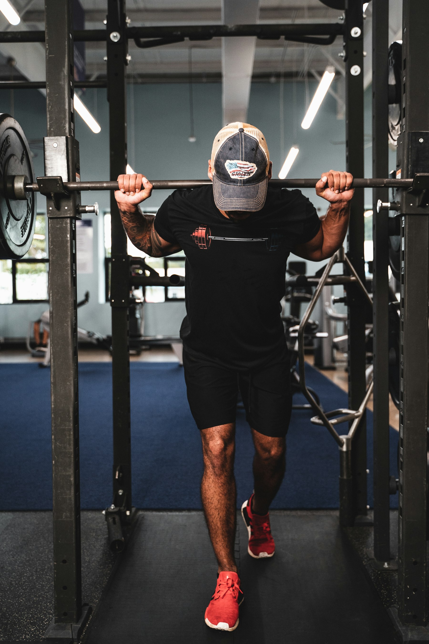 A man performing a barbell back squat in a power rack at the gym, representing strength training for long-term capacity