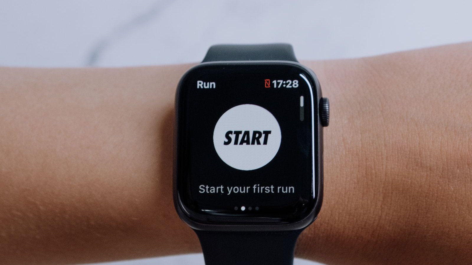Smartwatch on a wrist showing a running app prompt to start your first run