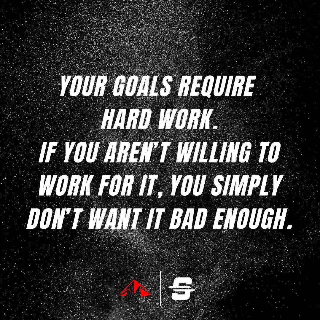 Mountain biker jumps over a dirt mound with snow-capped mountains.