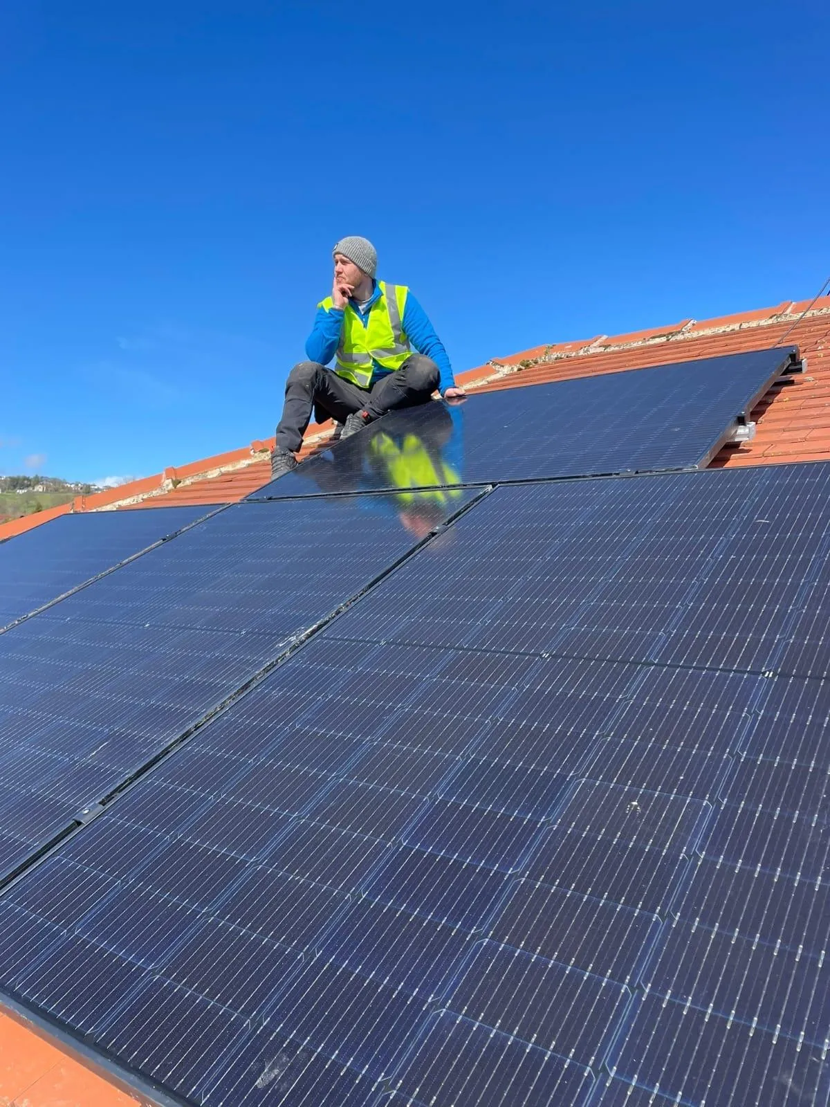 Tom Manning, director of Elektron Energy Services, sitting on the roof with installed solar panels in West Yorkshire