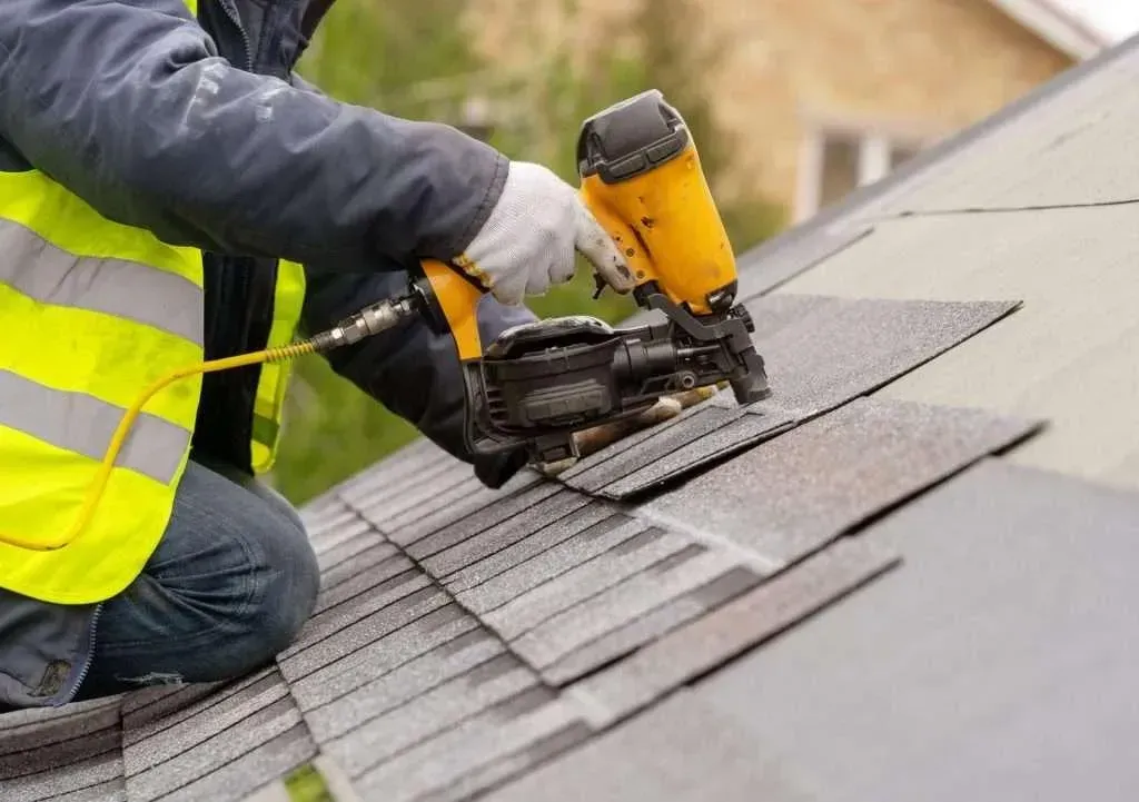 Roof repair technician fixing damaged shingles