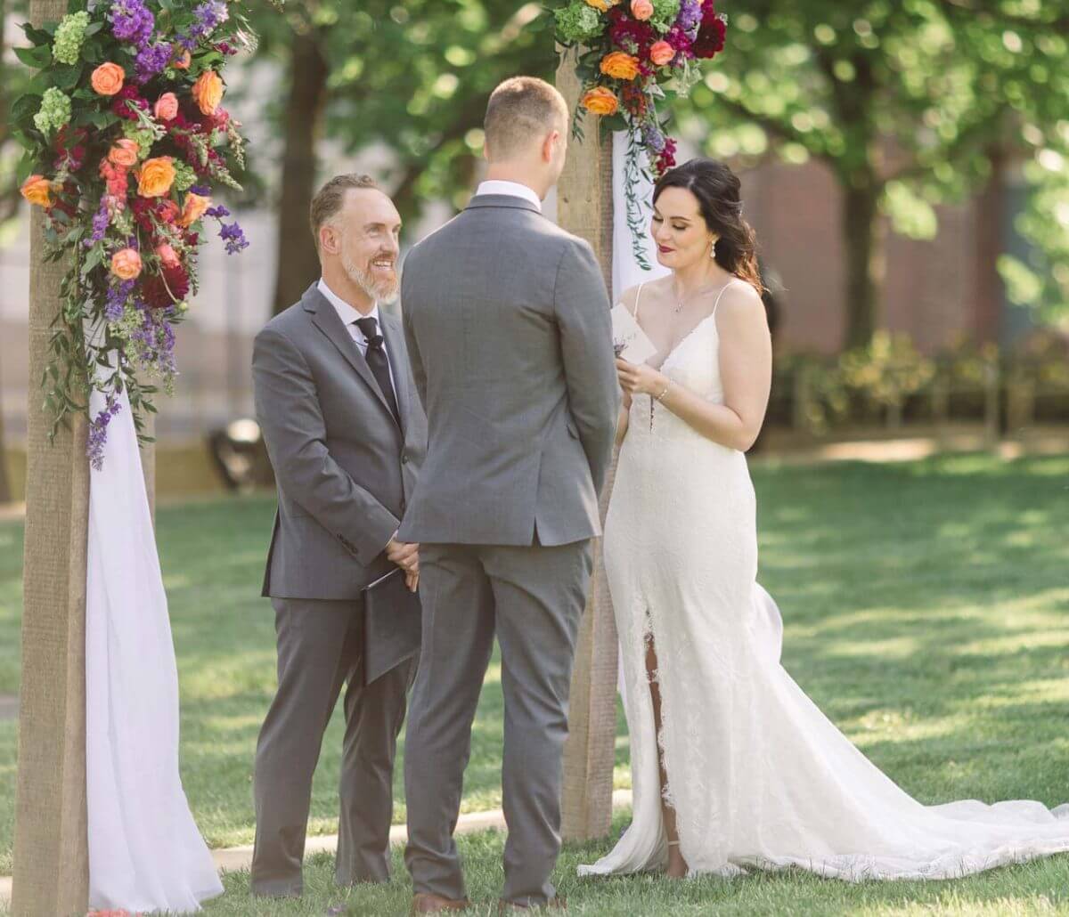 Wedding officiant speaking to a happy couple during an outdoor wedding.