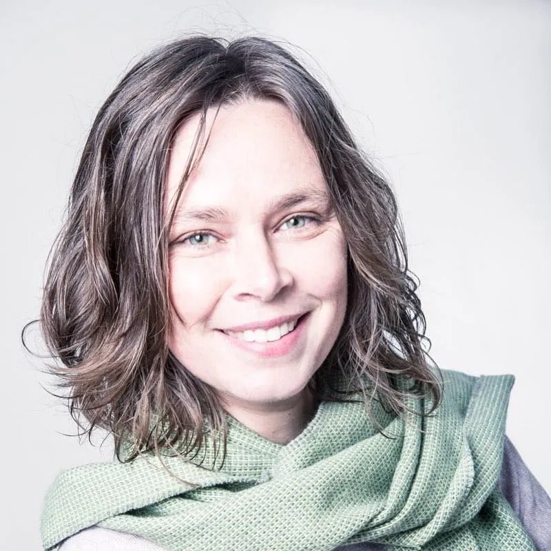 a close up of Minky (white woman with short brown hair) who is w | Working With the Impact of Clinical Practice  Tempo Therapy and Consultingaring a sage green scarf