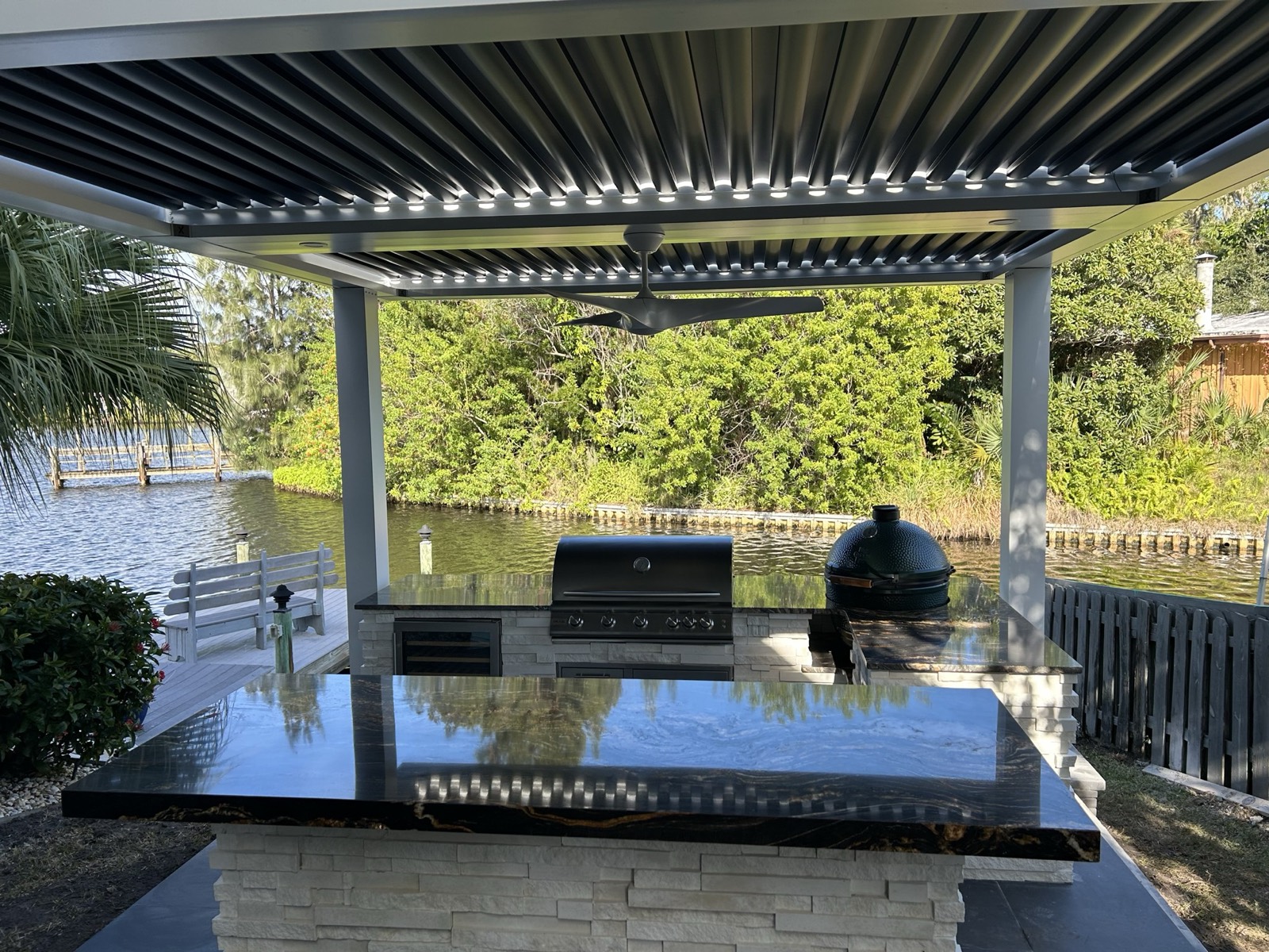Modern slat pergola over an outdoor kitchen at dusk, custom built in Melbourne, FL