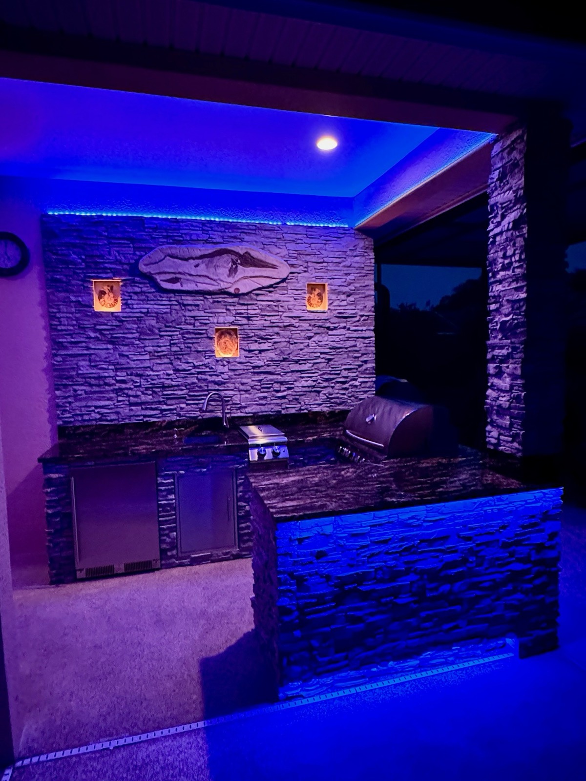 Outdoor kitchen and living area glowing with LED lighting in the evening, Brevard County FL