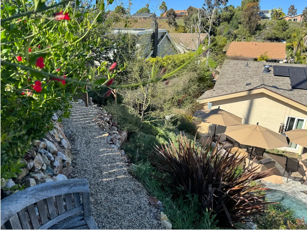 Stone-lined walkway looking toward a home with native landscaping.