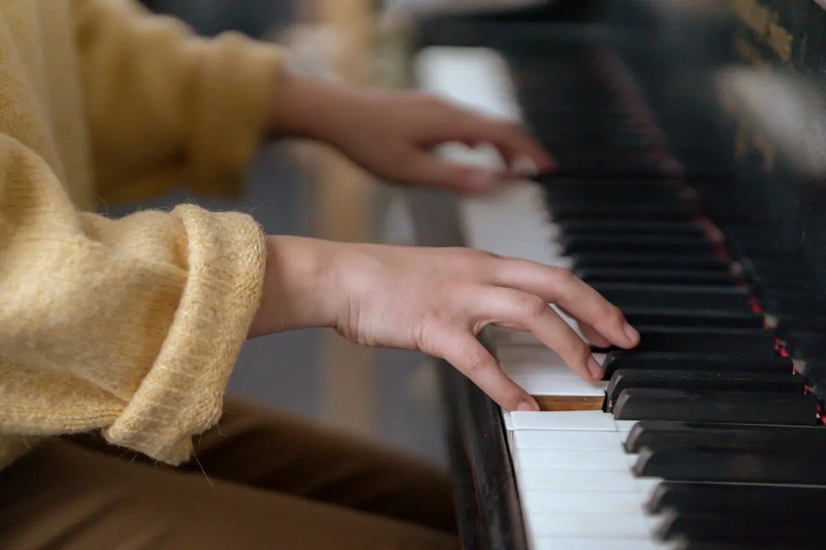 Hands playing piano in a warm creative studio session at Visionary Music Academy