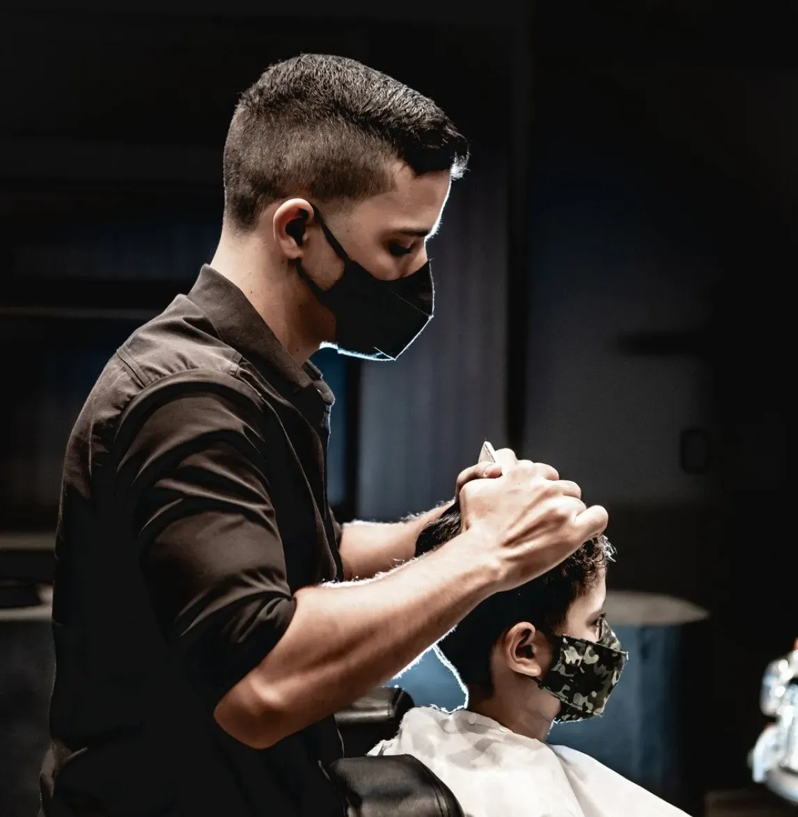 Mann schneidet einem Kind die Haare