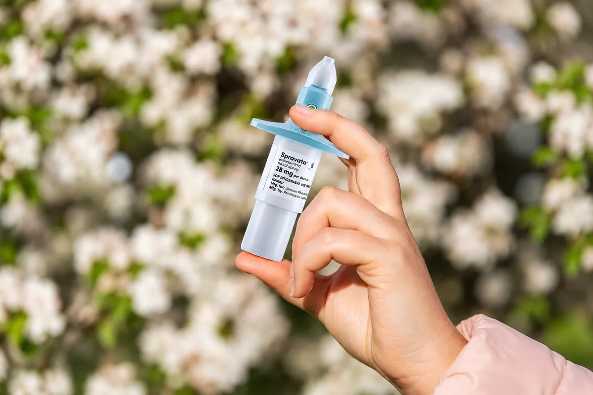 Hand holding a SPRAVATO nasal spray device