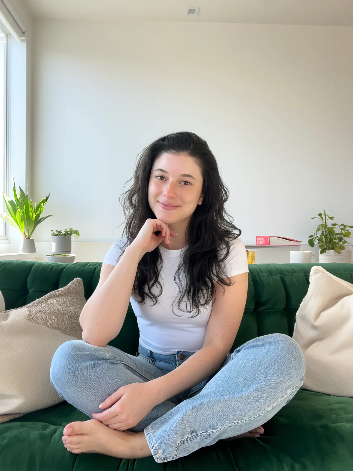 Barbara Guimarães sitting on a bench outside a coffee shop, wearing a denim jacket and holding a cup of coffee while looking off to the side with a soft smile.
