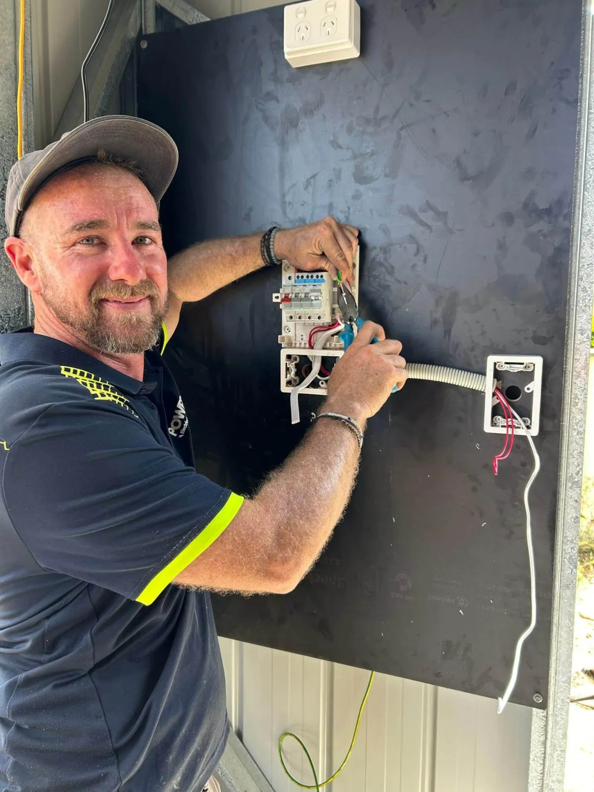 Power On Electrical technician servicing an outdoor air conditioning condenser unit beside a Caboolture home