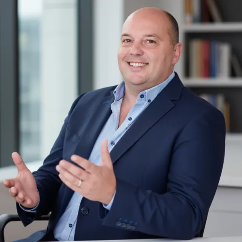 Senior AI advisor standing in a modern boardroom, conveying authority and calm leadership.