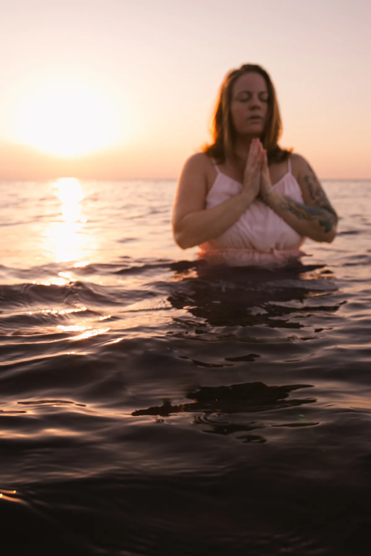 A serene woman quietly journaling in a warm, sunlight-filled space surrounded by gentle earth tones