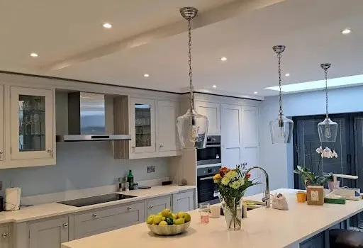 Modern kitchen with pendant lights above the island and recessed LED ceiling spotlights illutrating Electro Virium Ltd's lighting installation services