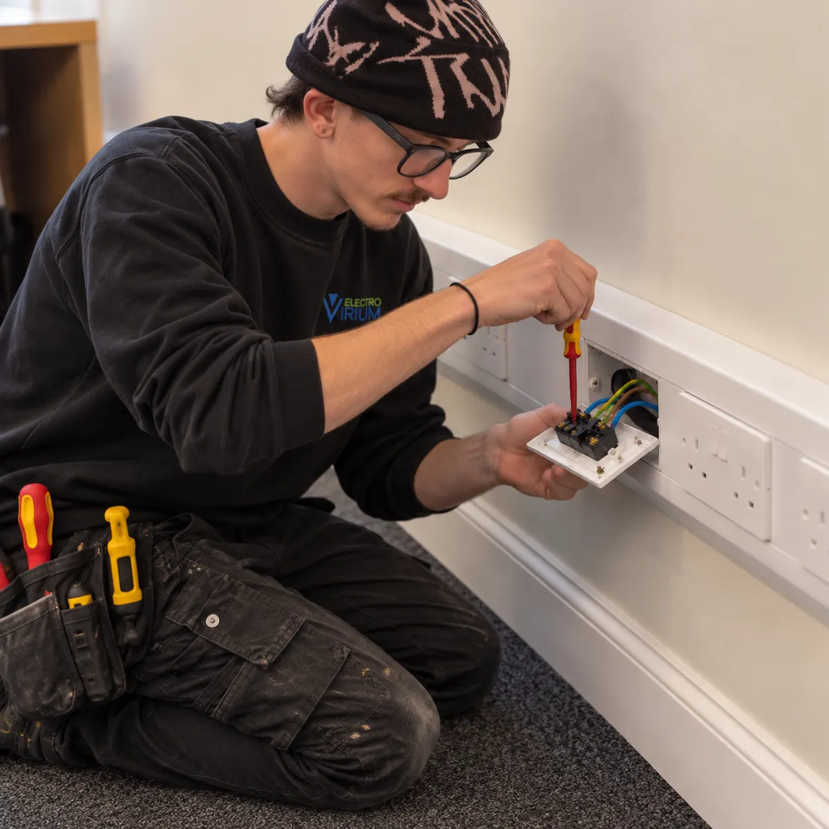 Max from Electro Virium Ltd installing electrical power and data sockets into dado trunking in a commercial office