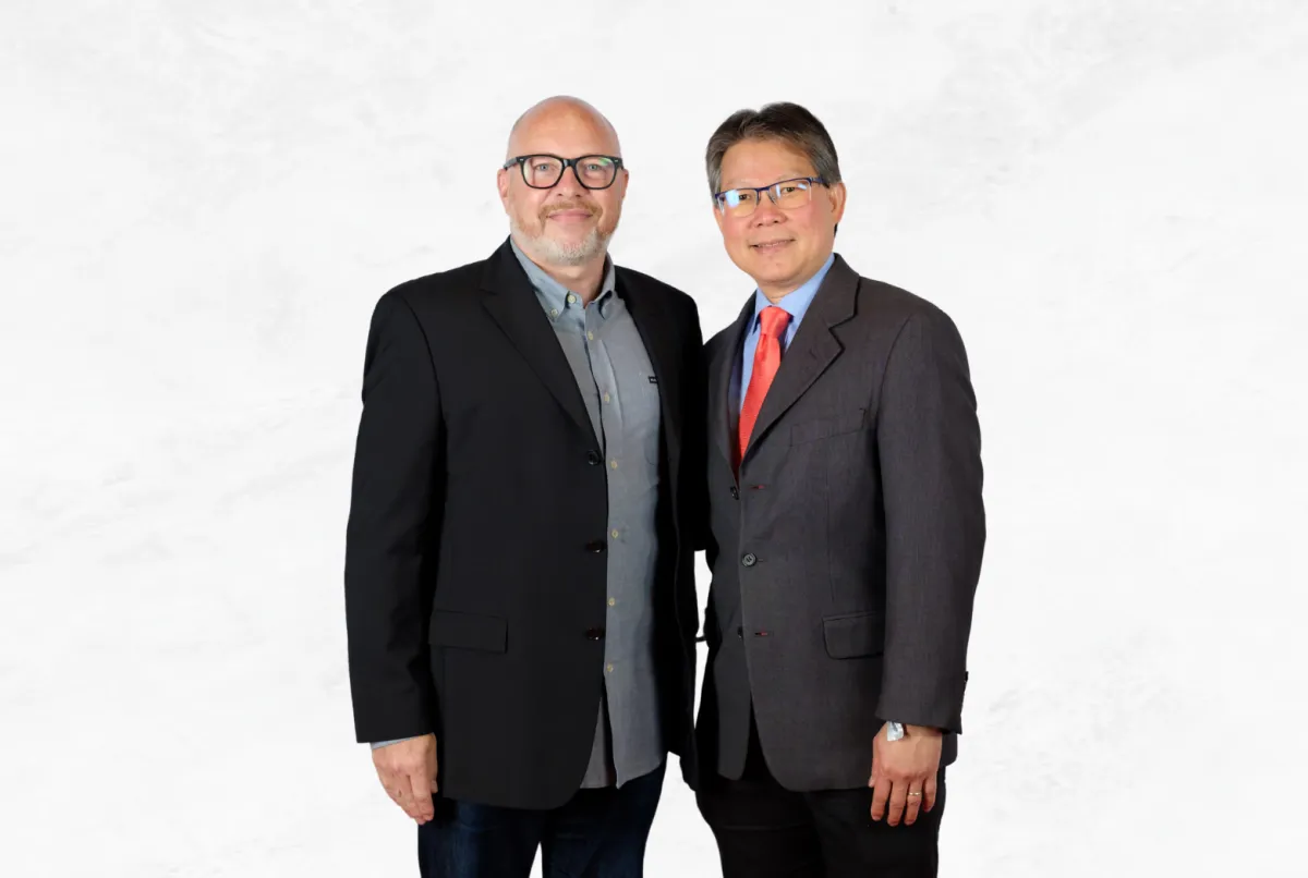 Sadikin Budiman standing with Barney Waters in a formal portrait, both in business attire against a white background.