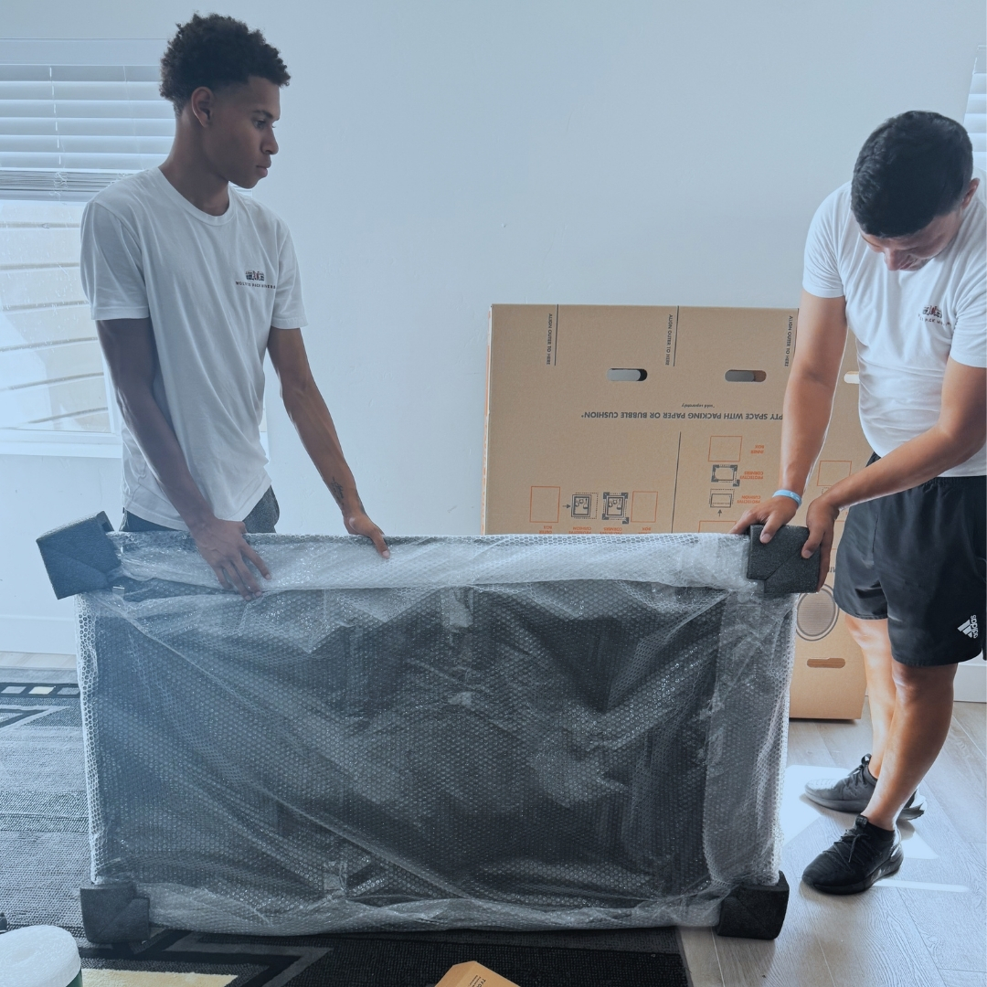 man in blue crew neck t-shirt standing beside brown cardboard boxes