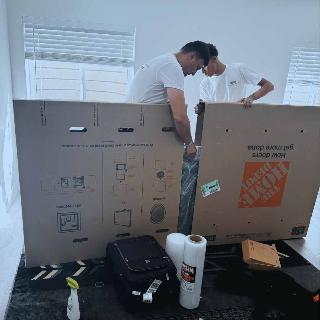 man in blue crew neck t-shirt standing beside brown cardboard boxes