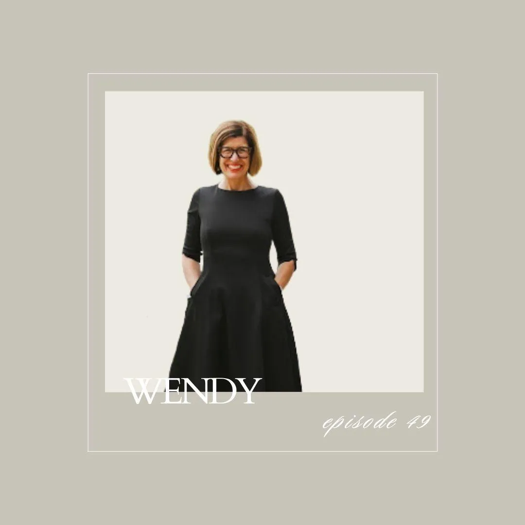 Smiling woman in a black dress with hands in pockets, standing confidently against a light background. Wendy Harrop. By Chance Avenue for childless women.