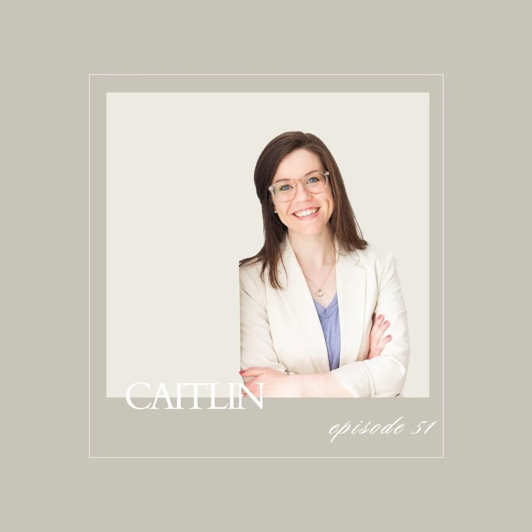 Woman with glasses smiling confidently in a light blazer, arms crossed, on a neutral background. Caitlin Estes. By Chance Avenue for childless women.