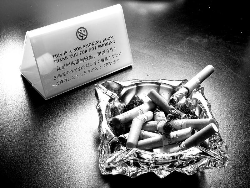 An overflowing ashtray next to a sign saying this is a non-smoking room