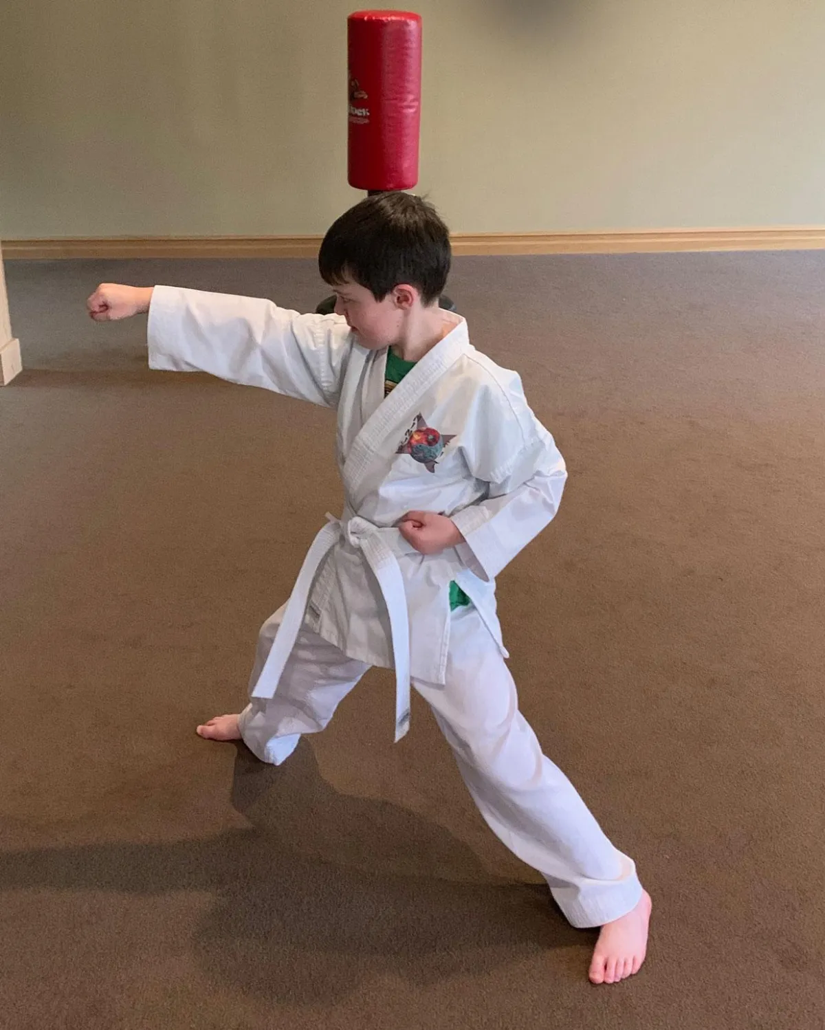young boy in Ninja Fit karate uniform holding karate punch in good stance while keeping eyes focused on punching knuckles