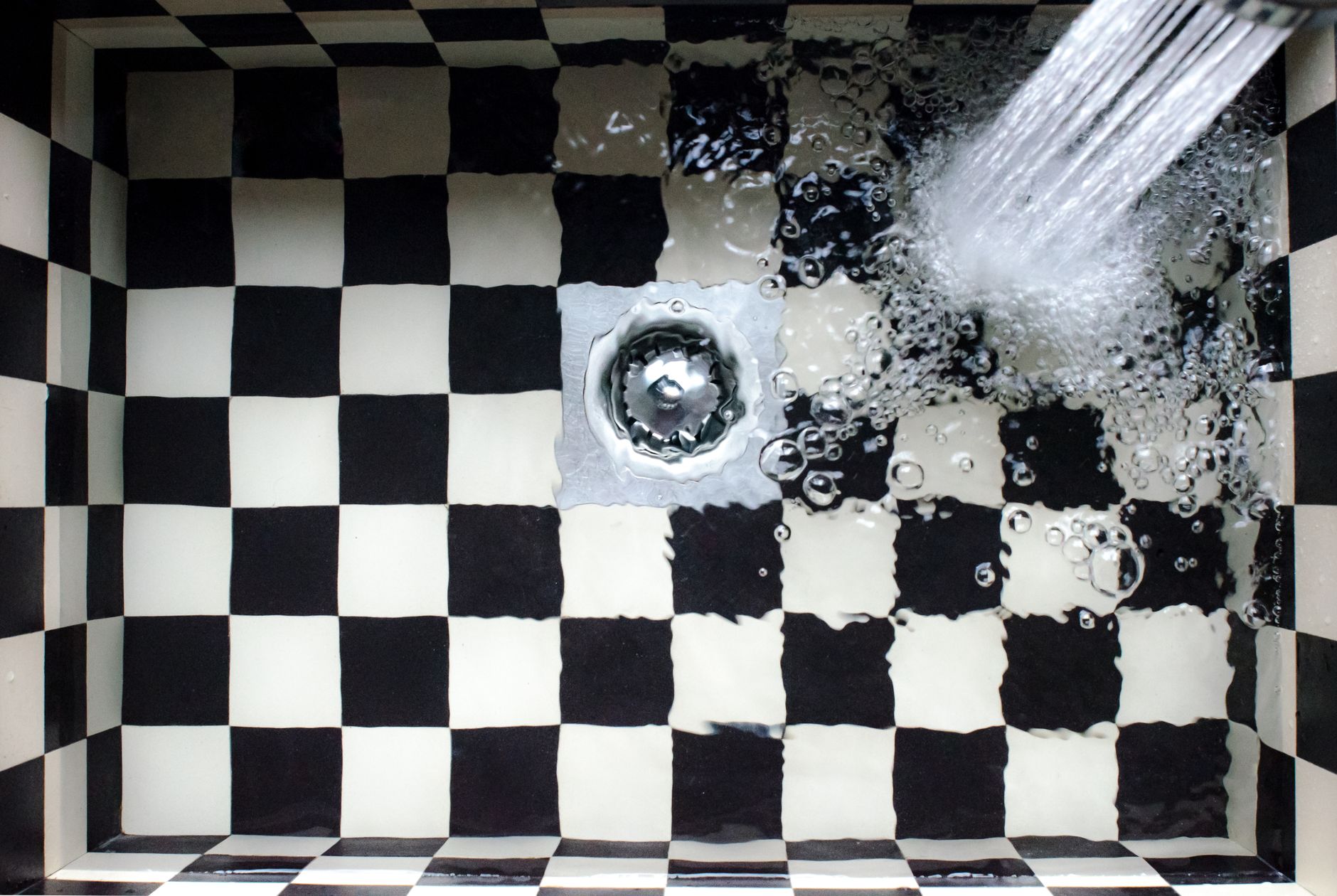 Plumber using a pipe wrench to fix a leaking bathroom faucet