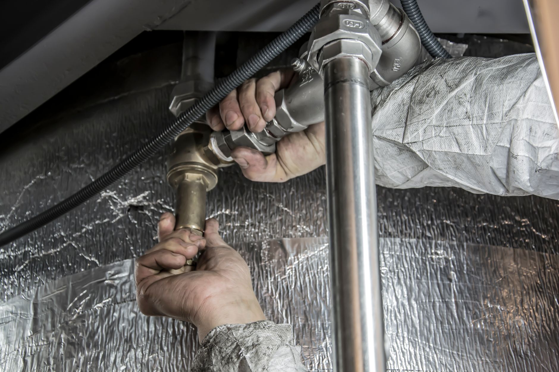 Plumber inspecting a leaking tank water heater in a Miami garage