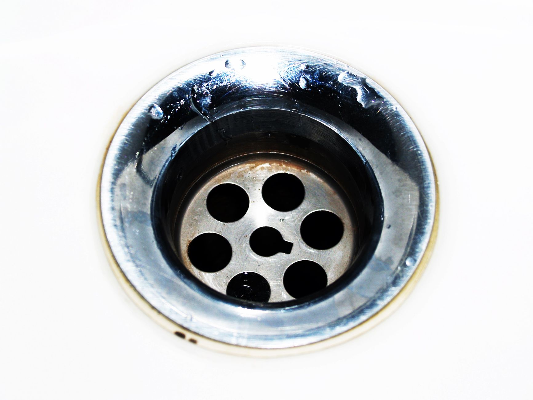 Plumbing technician inspecting copper pipes under a kitchen sink