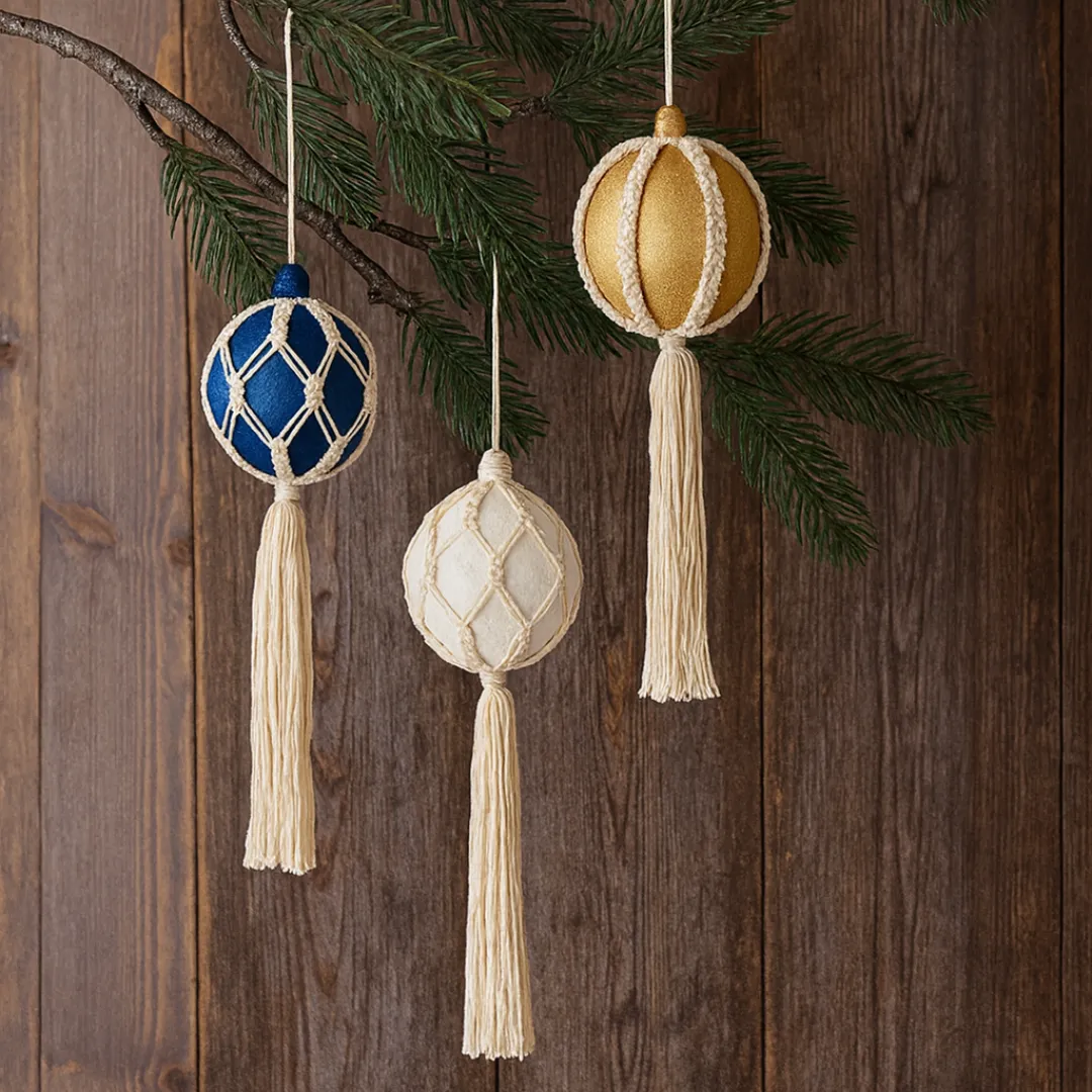 Handmade macramé Christmas baubles with white cord and tassels, hanging from a rustic tree branch against a wooden background – perfect for festive boho décor or macramé craft workshop inspiration
