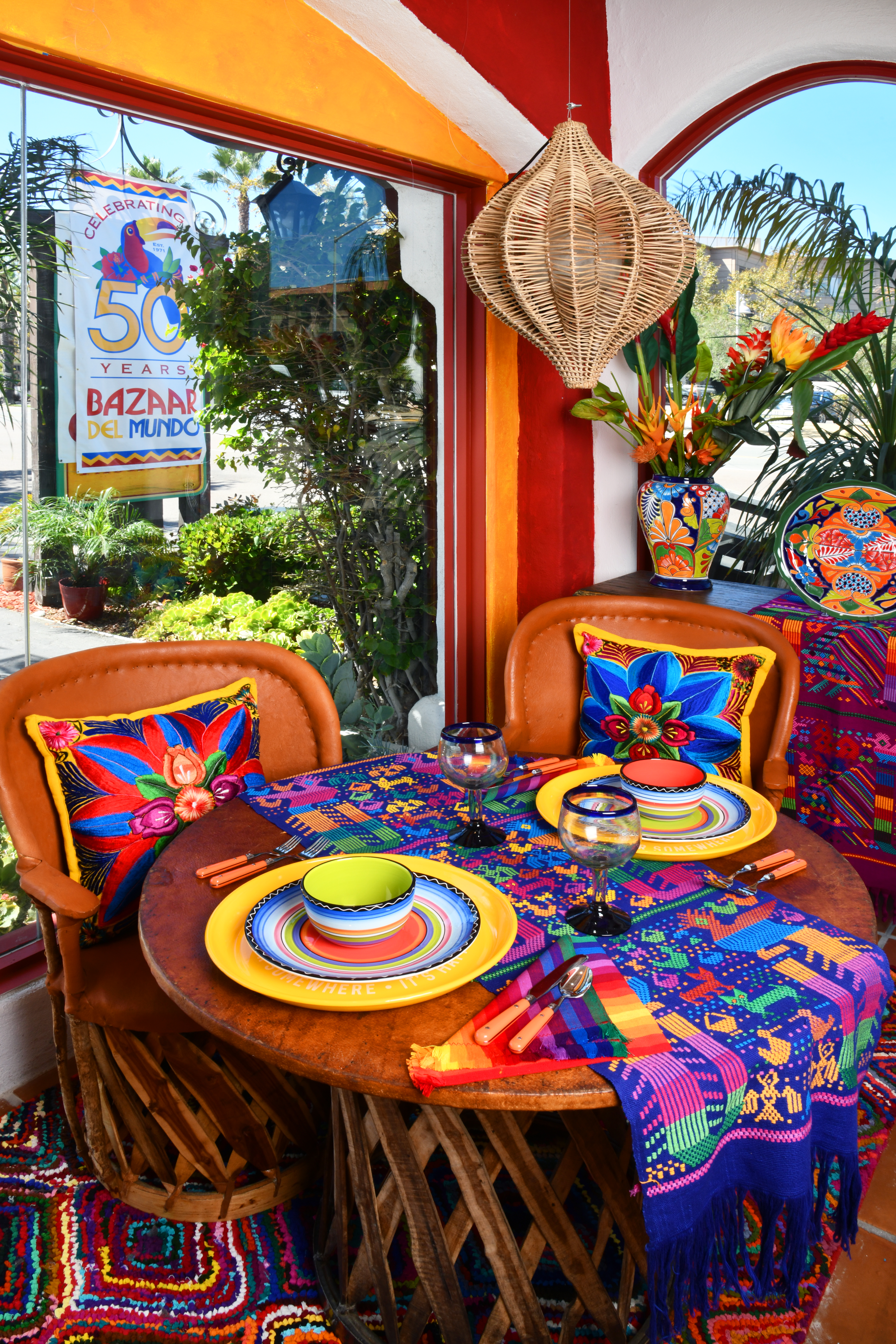 Vibrant handwoven Mexican textiles and artisanal embroidery arranged in an authentic courtyard setting