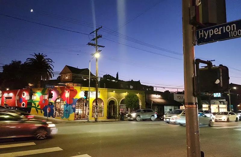 A dusk view of Silver Lake, California, showing a street corner with colorful murals