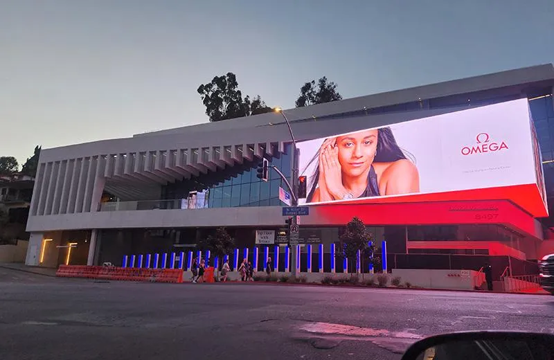  A view of West Hollywood at dusk, with a large, illuminated billboard showing an Omega advertisement
