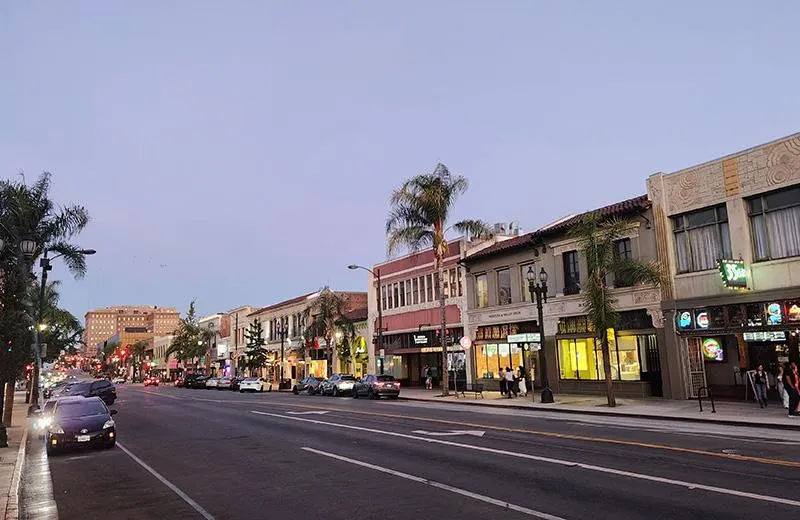 A nighttime view of a street in Pasadena, California, with cars and storefronts lining the road