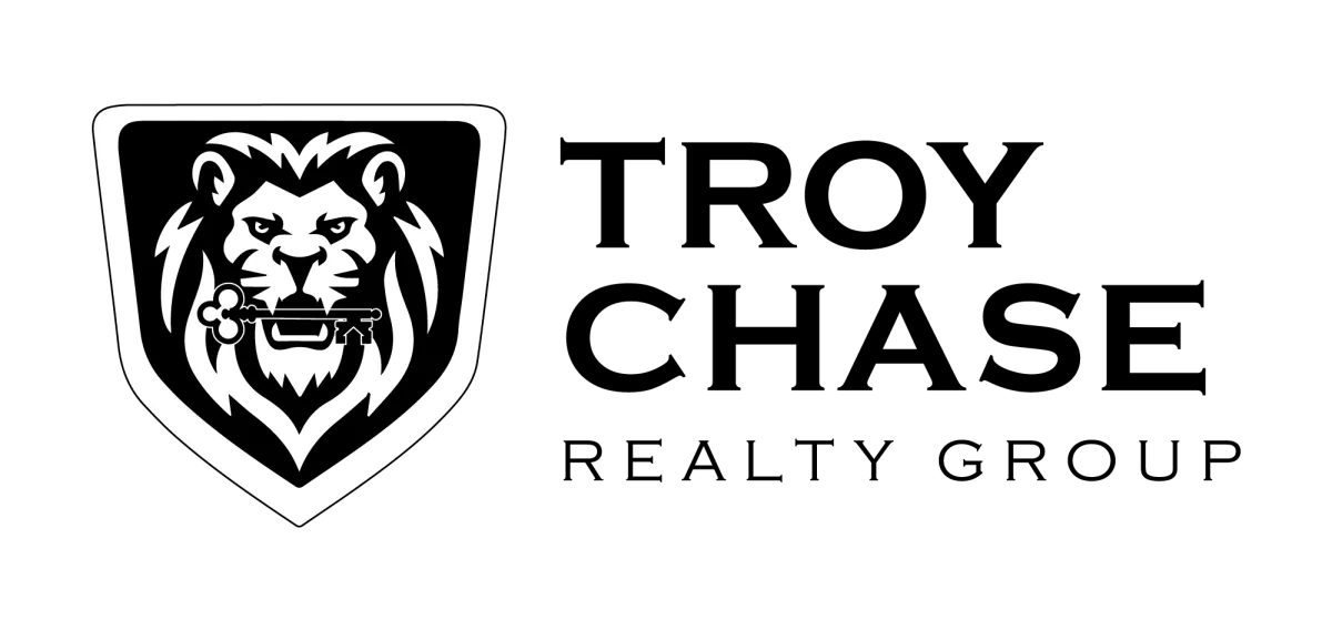 Lion logo with a key in its mouth, representing strength and security, relevant to real estate services offered by Troy Chase Realty Group.