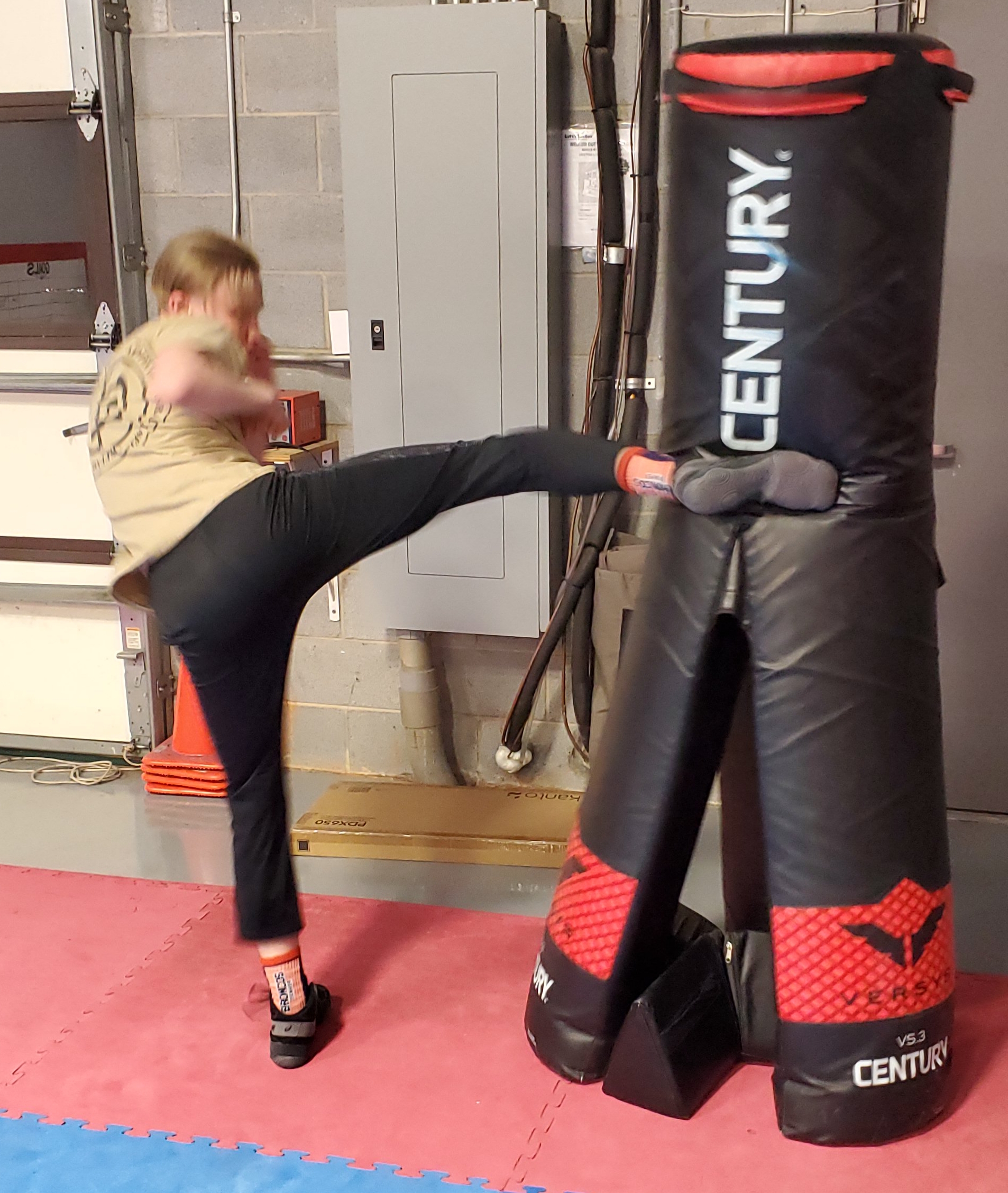 Teen boy practicing a roundhouse kick during self-defense training at Krav Maga Lake Norman
