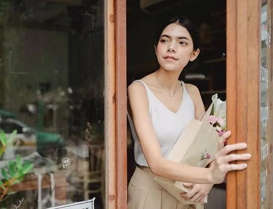 Woman carrying groceries pauses at doorway to scan surroundings, showing situational awareness.