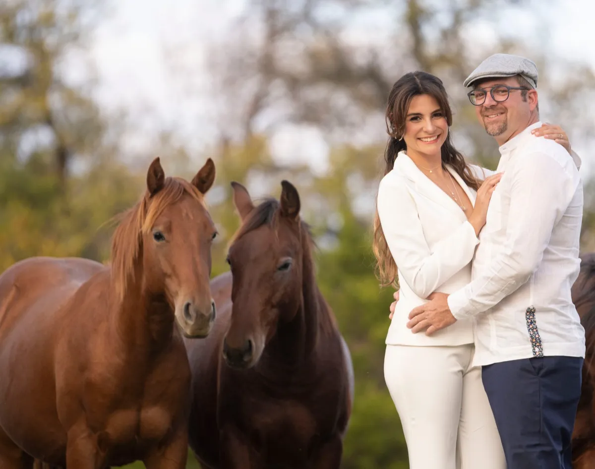 Jose and Astrid Sigala embracing next to two horses