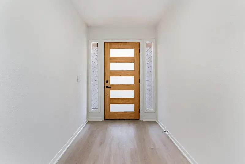 Renovated entry hallway with a wood front door and light wood-look flooring