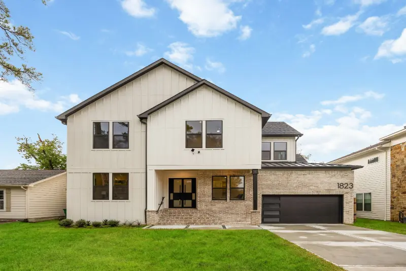 Two-story new construction home with white siding, brick accents and a two-car garage