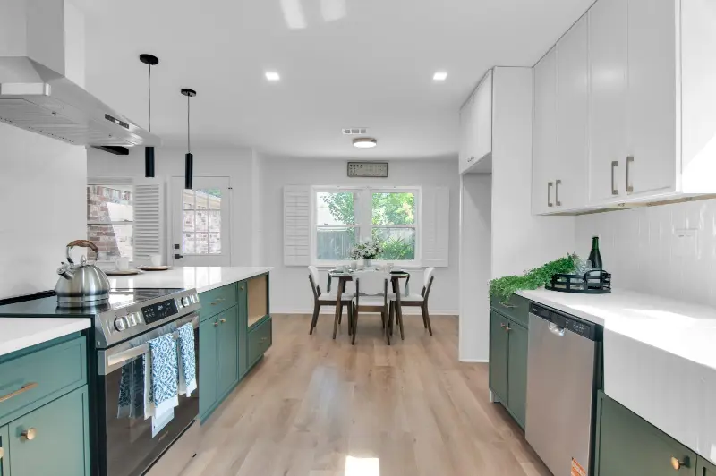Renovated kitchen with green lower cabinets, white upper cabinets and a dining area