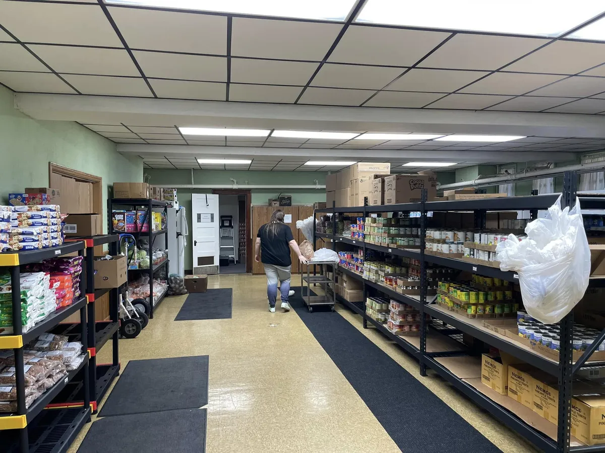 Documentary still of fresh produce, pantry shelves, and volunteers preparing community grocery baskets at Evanoff Center