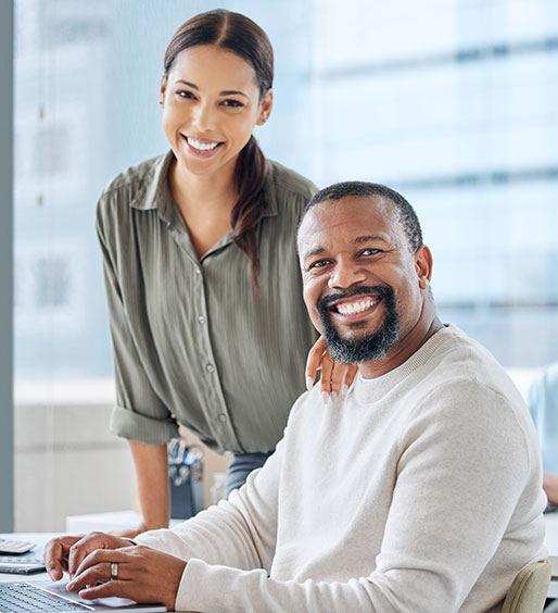 Agente de seguros bilingüe sonriendo mientras revisa documentos de póliza en una oficina moderna y luminosa.