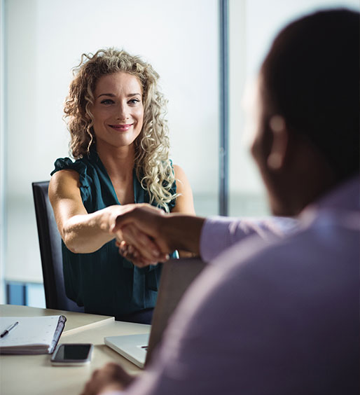 Agente de seguros bilingüe sonriendo mientras revisa documentos de póliza en una oficina moderna y luminosa.