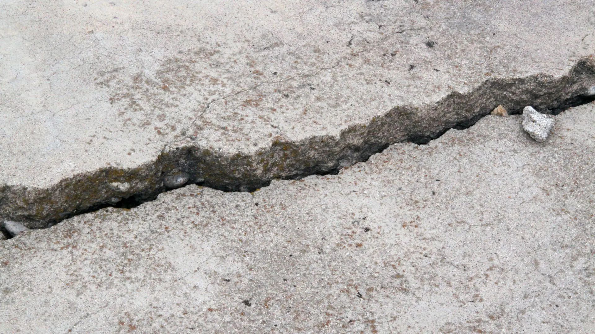 Cracked concrete driveway in Lansing, MI showing sinking slab before concrete leveling services.